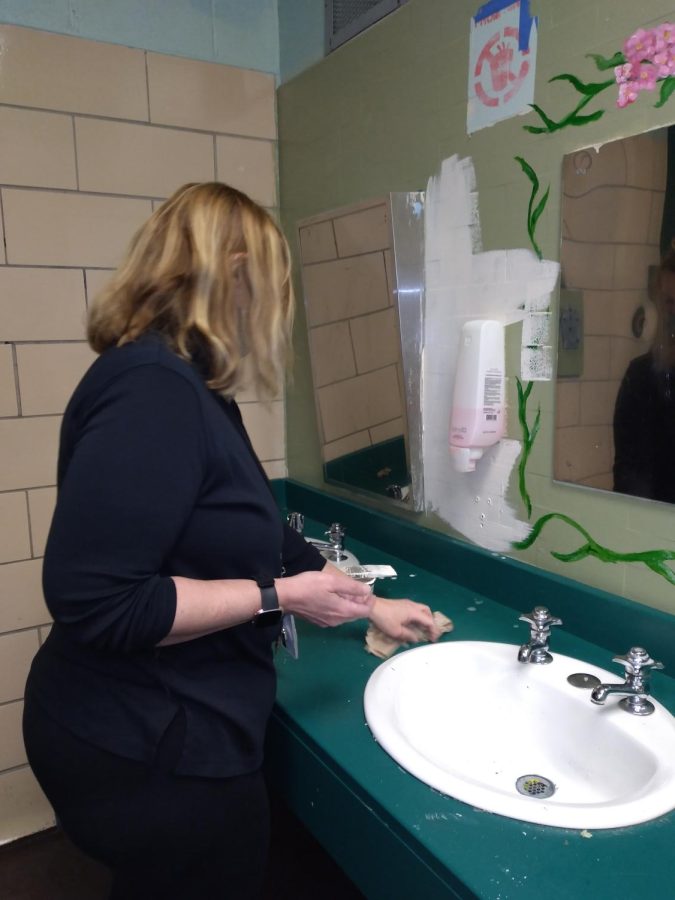 Christina Whitt, mural club faculty advisor, wipes the girls’ bathroom counter