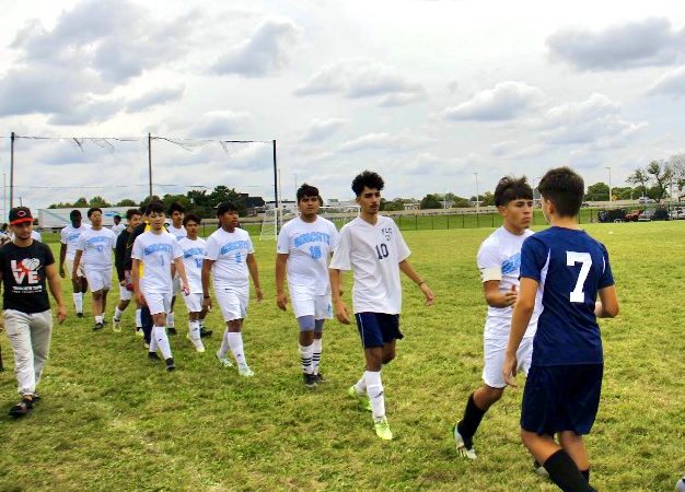 Boys soccer team lines up to shake the hands of their competitors after the game ends.
