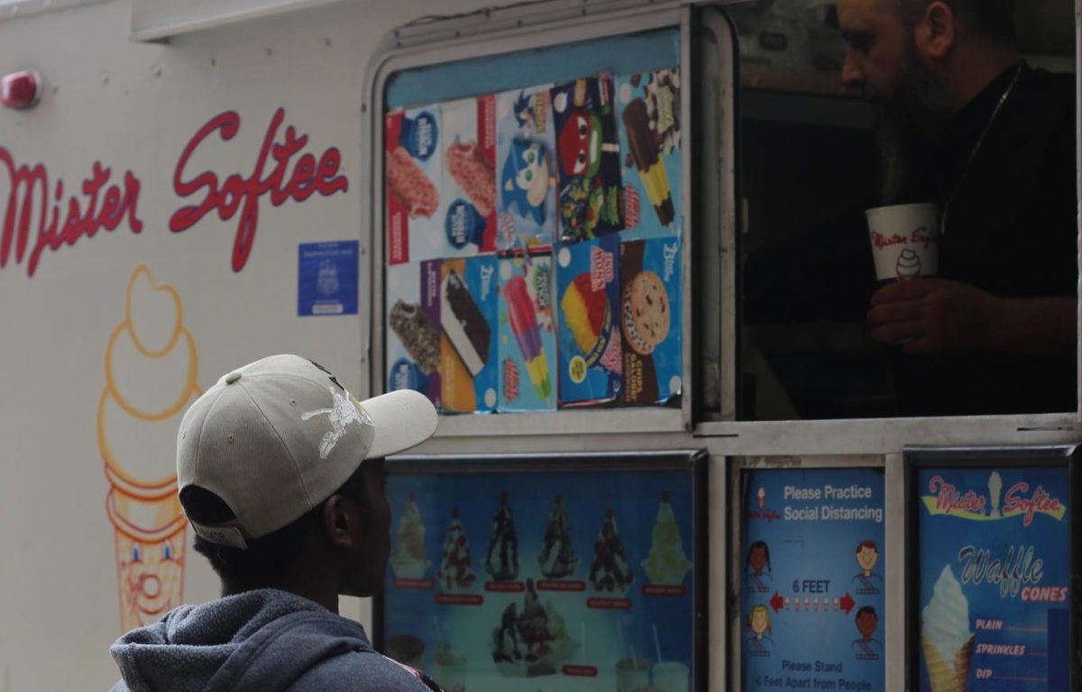 FLC student reaching out for their order in front of the Mister Softee truck.